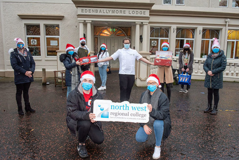 Group of students standing outside care home wearing Santa hats and face coverings