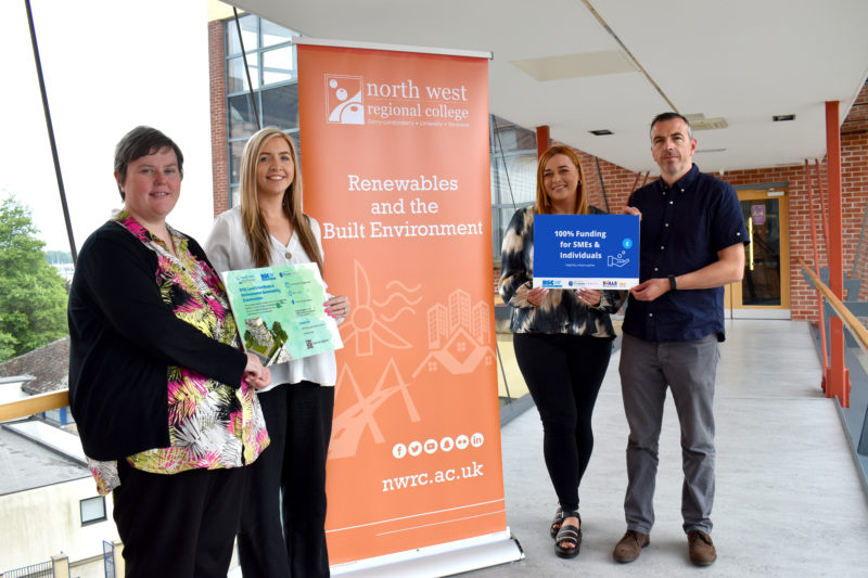 Four people standing beside signage for environmental sustainability