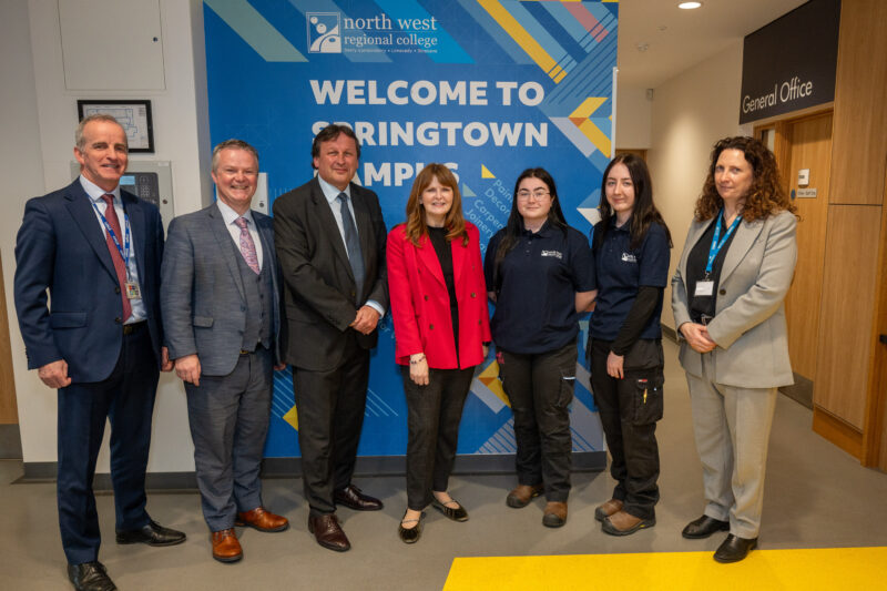 Group of seven stand in a row at an internal wall that says springtown campus