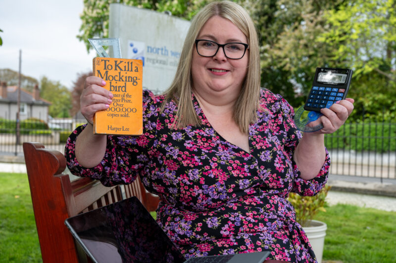 Lady sitting on a bench with a calculator, book and laptop in her hand