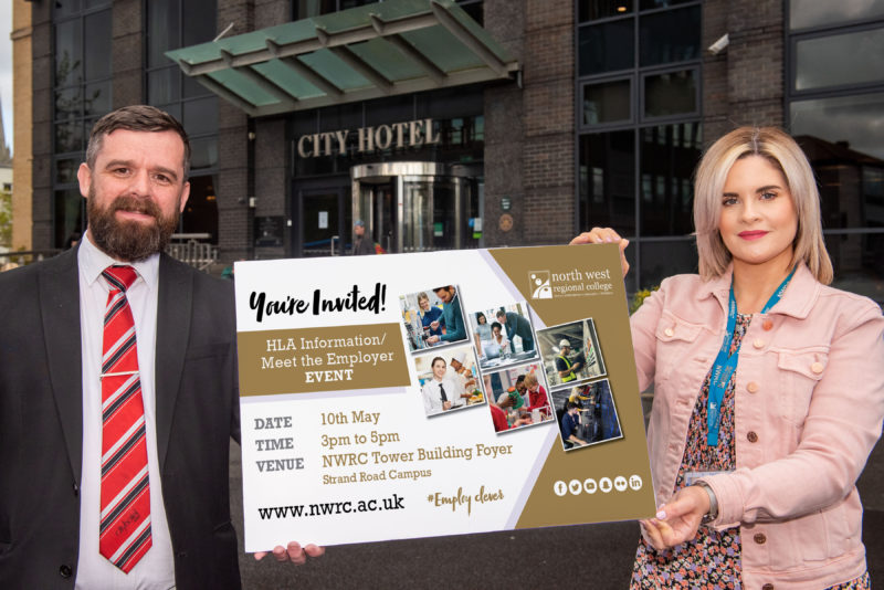 Man and woman pictured outside hotel holding a sign advertising the HLA event at NWRC on May 10.