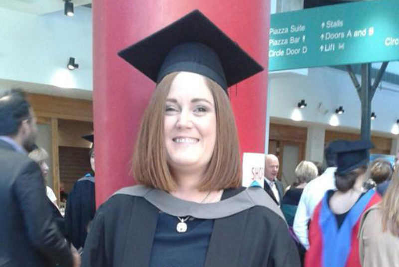 NWRC student smiling at graduation ceremony wearing graduation robes and mortarboard