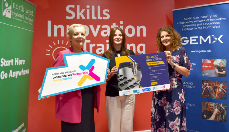 Three women holding up signs about the Advanced Manufacturing Academy