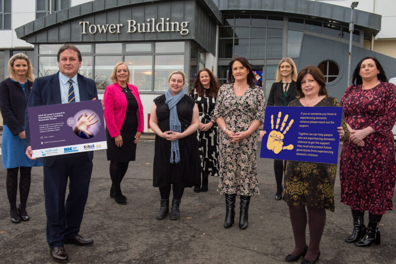 Group of people pictured outside NWRC holding a board raising awareness of the 16 days of action.