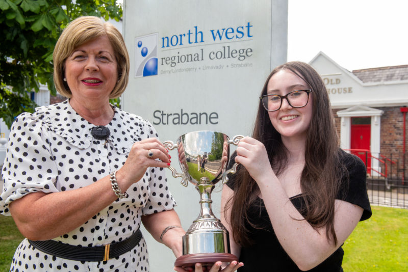 Two people pictured outside the campus with a trophy