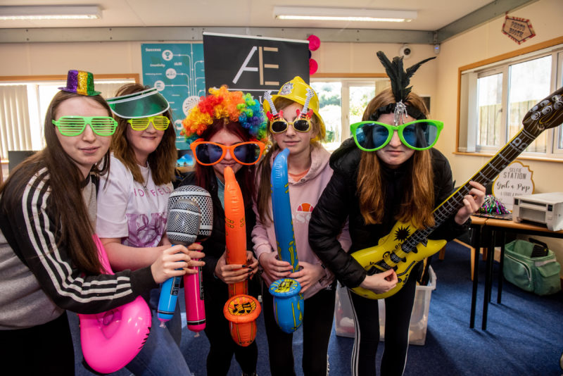 Group of 5 female students at Freshers Day, wearing colourful glasses, wigs, hats and blow-up guitars