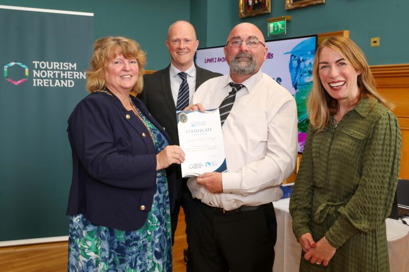 4 people in a group with two people holding a certificate at the front.