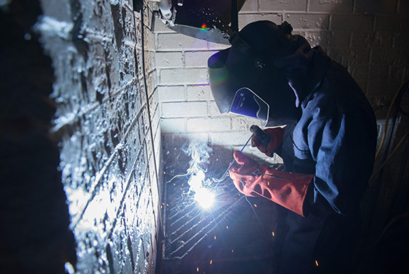 Welder in protective clothing, welding in workshop