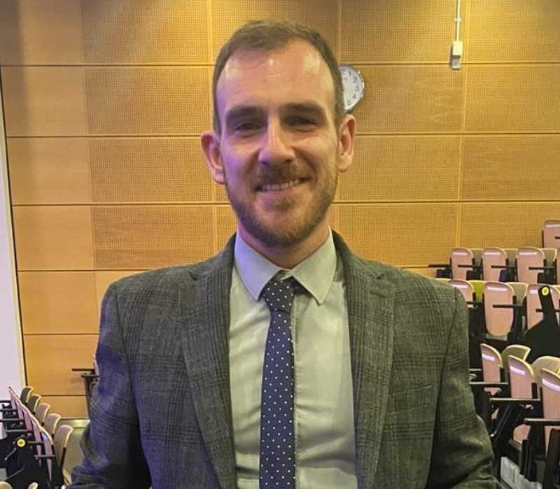 Man pictured in a lecture theatre smiling