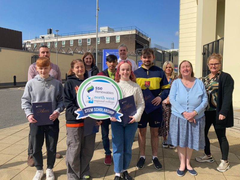 group of students and lecturers pictured outside the college holding a sign for SSE renewables scholarships