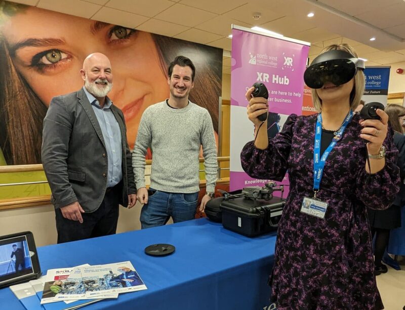 Woman pictured wearing a virtual reality headset pictured with two men