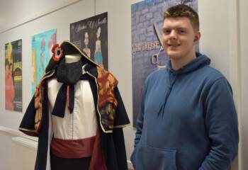 Male student beside a mannequin with a costume on it