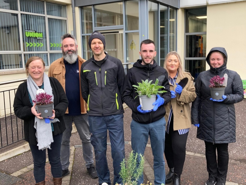 students and staff pictured holding plants