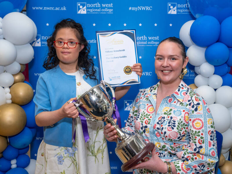 two ladies in front of NWRC branding holding a certificate and tropy