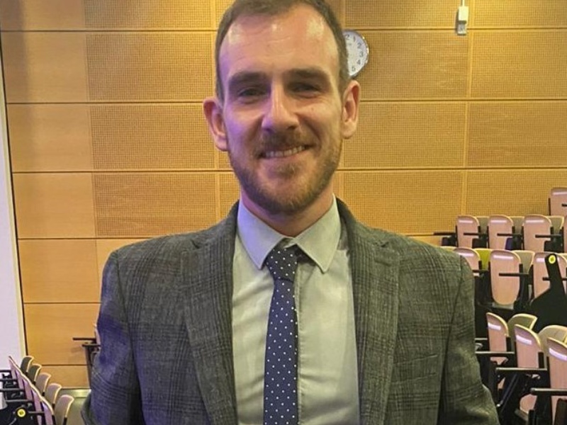 Man pictured in a lecture theatre smiling
